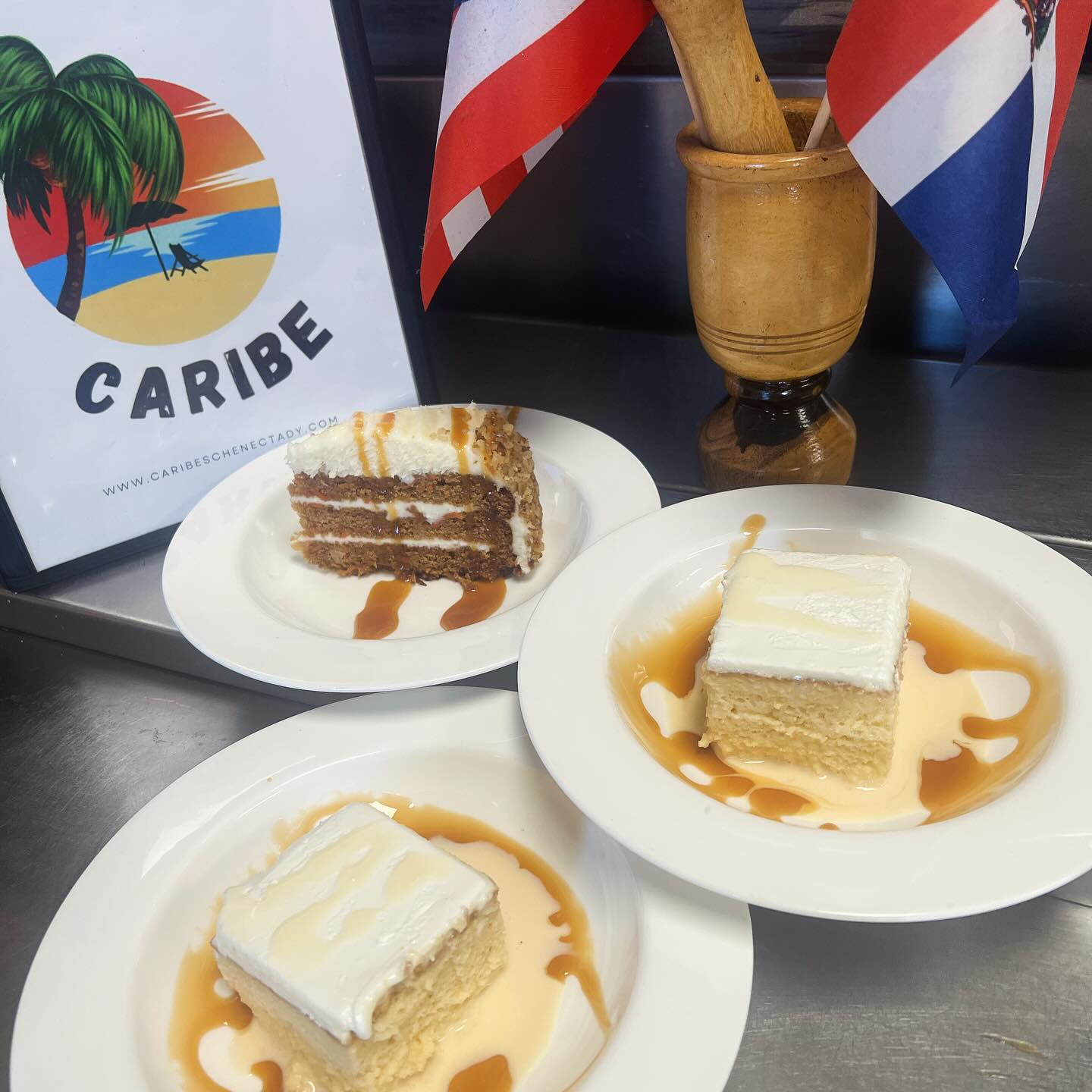 Slices of tres leches and carrot cake with caramel drizzle and a Caribe sign