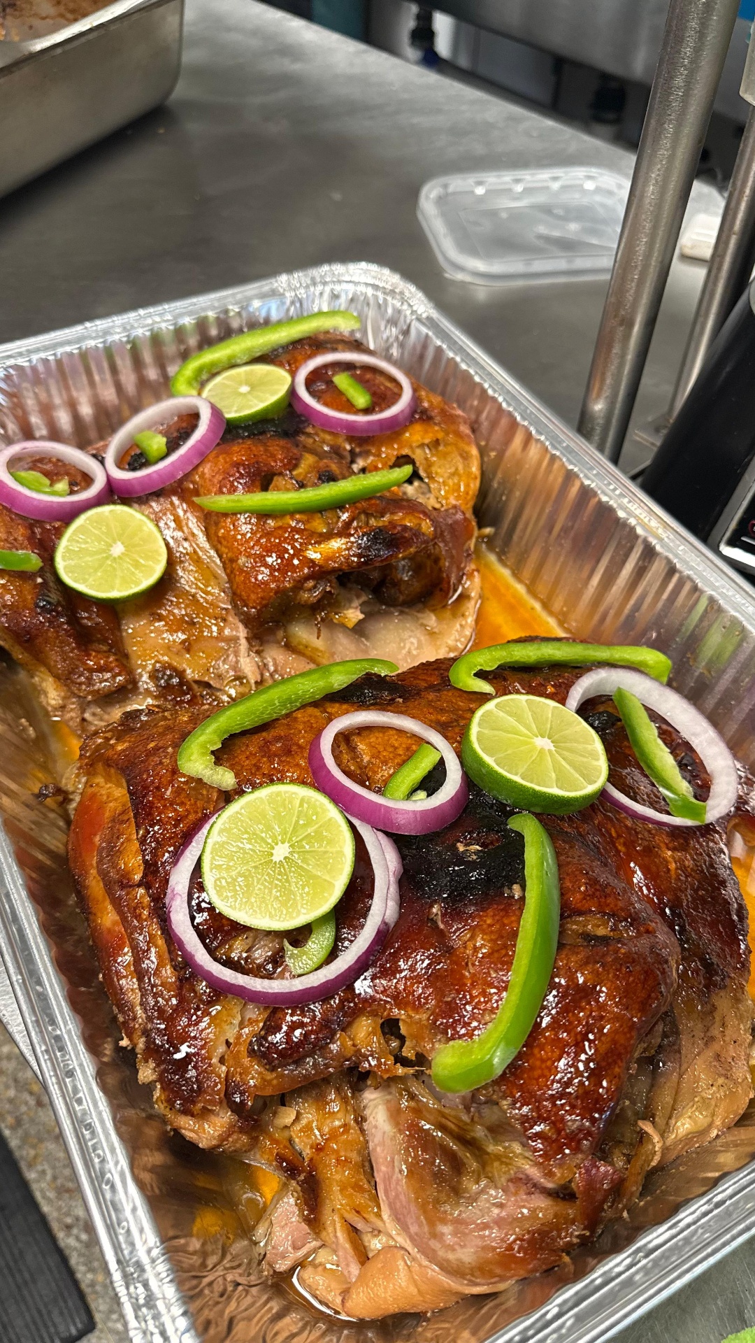 Caribe Catering trays of roasted pernil topped with lime, onion, and bell pepper