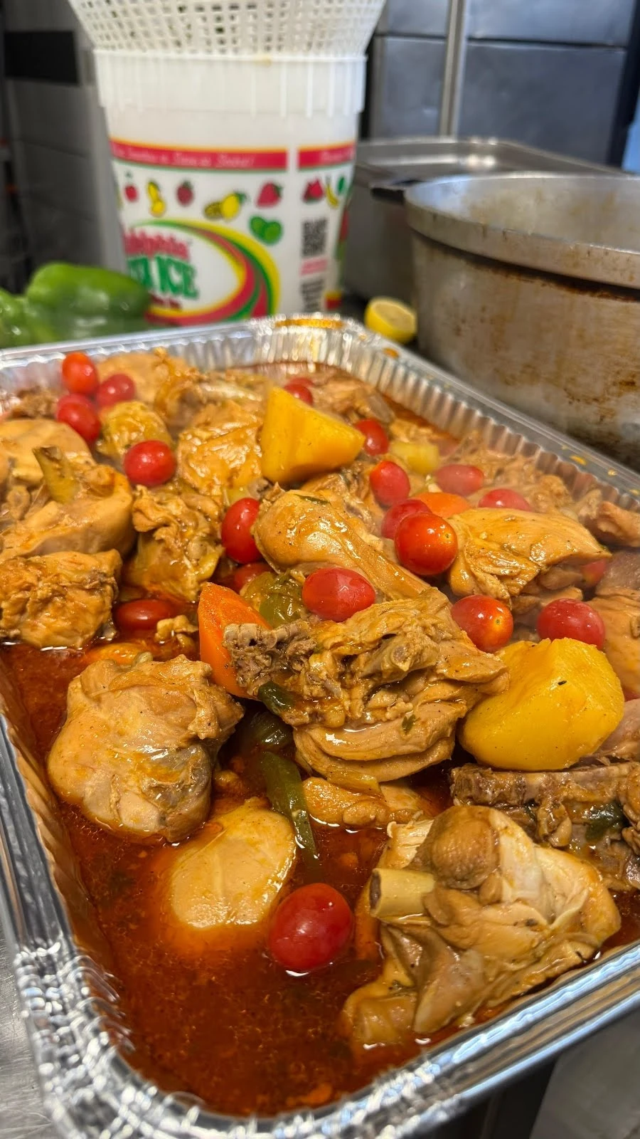 Caribe Catering tray of stewed chicken (pollo guisado) with tomatoes and potatoes
