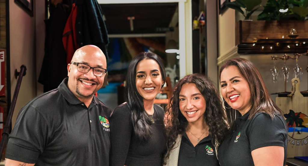 The Fabian family gathered together under the Caribe Vibes neon sign