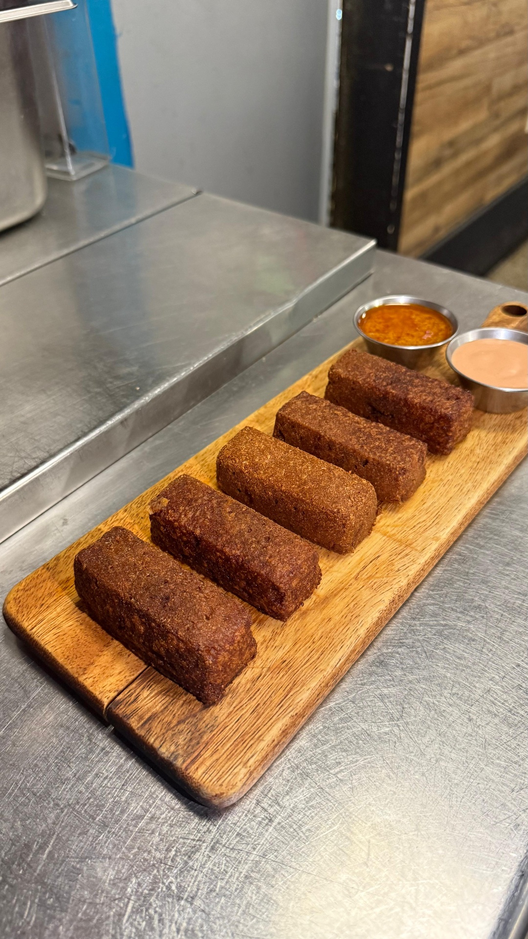 Wooden board of golden Dominican kipes with house dipping sauces at Caribe