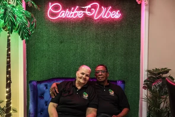 Mami and Pure Fabian under the Caribe Vibes neon sign